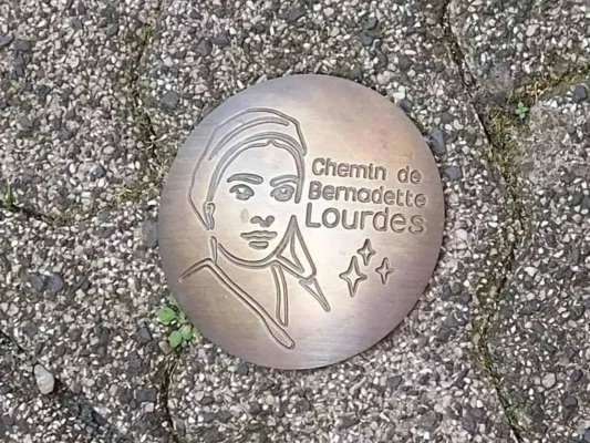 Formella sul pavimento del santuario di lourdes con volto di santa Bernadette